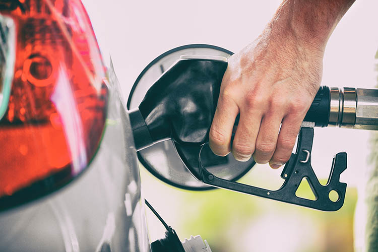 Persona que bombeja combustible per omplir el dipòsit d'un cotxe a una gasolinera. Mà d'home que sosté la broqueta per repostar.